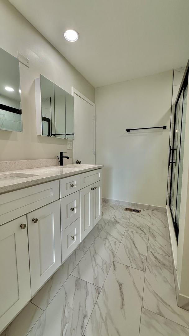 bathroom with a shower with door and vanity