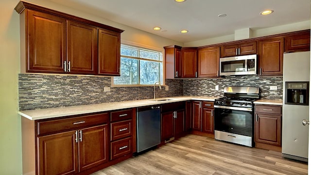 kitchen featuring appliances with stainless steel finishes, tasteful backsplash, light hardwood / wood-style floors, and sink