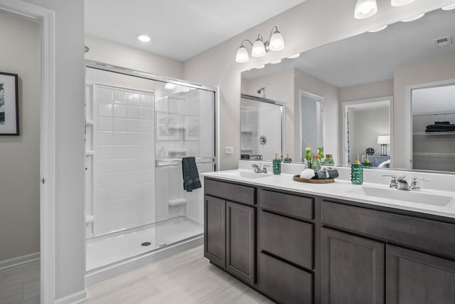 bathroom with a shower with shower door and vanity