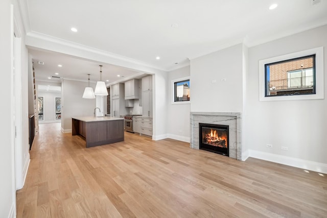 kitchen featuring pendant lighting, sink, plenty of natural light, stainless steel range, and a center island with sink