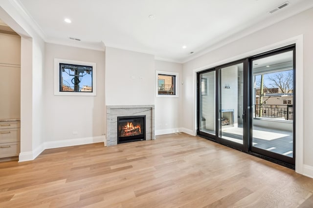 unfurnished living room featuring ornamental molding, a fireplace, and light hardwood / wood-style floors