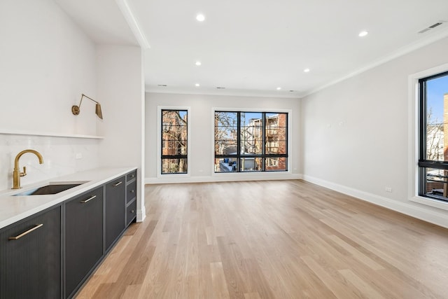 interior space featuring ornamental molding, sink, and light hardwood / wood-style flooring