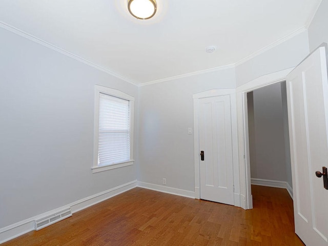 spare room featuring hardwood / wood-style floors and crown molding