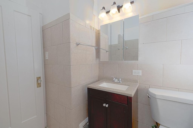 bathroom featuring vanity, toilet, and tile walls