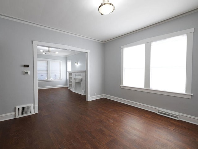 unfurnished living room featuring a fireplace, ornamental molding, dark wood-type flooring, and a healthy amount of sunlight