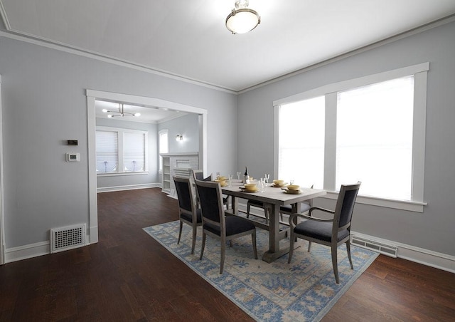 dining room with dark hardwood / wood-style flooring, an inviting chandelier, and ornamental molding