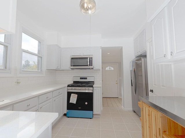 kitchen with light stone countertops, tasteful backsplash, stainless steel appliances, light tile patterned floors, and white cabinets