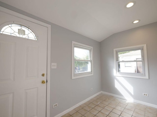 foyer entrance featuring a wealth of natural light, light tile patterned floors, and vaulted ceiling