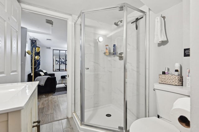 bathroom featuring toilet, a shower with shower door, and vanity