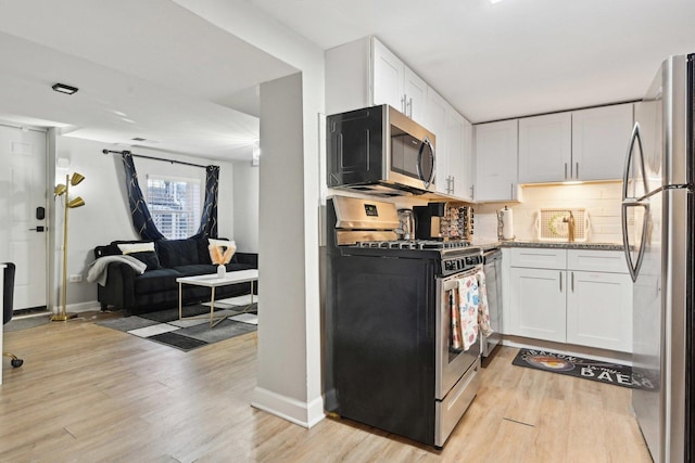 kitchen with white cabinetry, light stone counters, appliances with stainless steel finishes, and tasteful backsplash