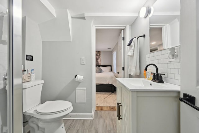 bathroom featuring decorative backsplash, hardwood / wood-style flooring, vanity, and toilet