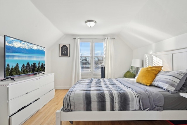 bedroom featuring light wood-type flooring and vaulted ceiling