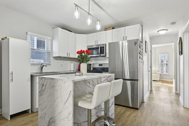 kitchen with sink, stainless steel appliances, a center island, and white cabinets