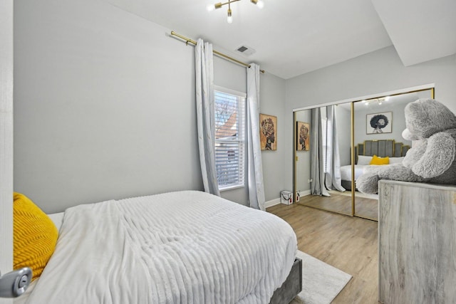 bedroom featuring multiple windows, light hardwood / wood-style flooring, and a closet