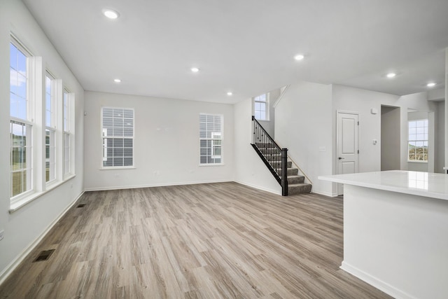 unfurnished living room featuring a wealth of natural light and light hardwood / wood-style floors