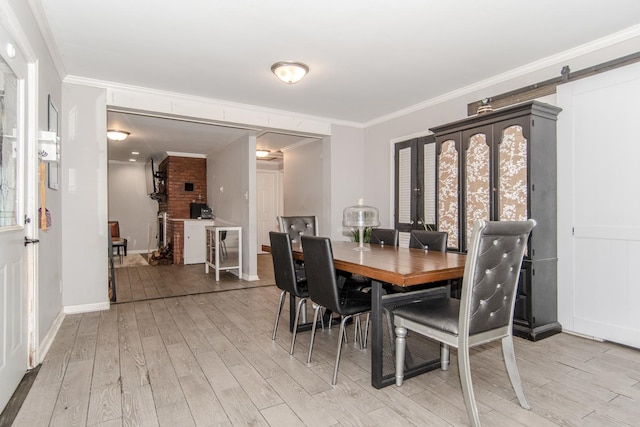 dining space featuring light hardwood / wood-style floors, a barn door, and ornamental molding