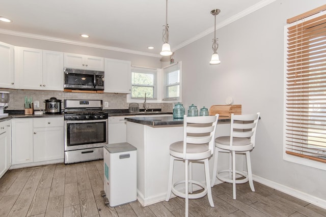 kitchen featuring stainless steel appliances, decorative light fixtures, light hardwood / wood-style flooring, a center island, and white cabinetry