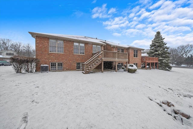 snow covered rear of property with cooling unit and a wooden deck