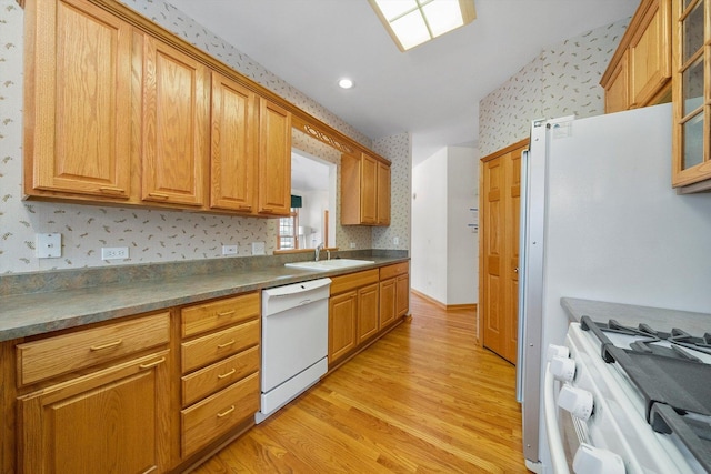 kitchen with light wood-type flooring, white appliances, and sink