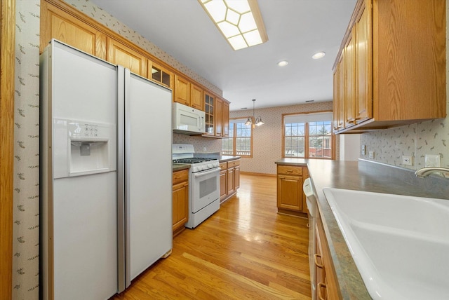 kitchen featuring pendant lighting, light wood-type flooring, white appliances, and sink