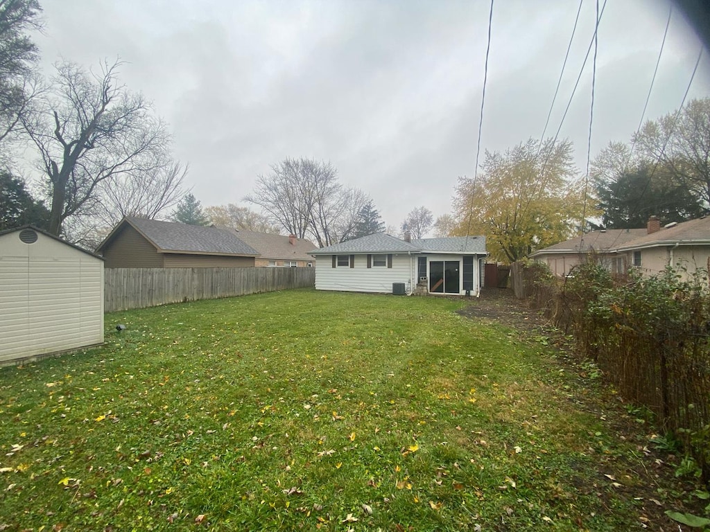 view of yard featuring an outbuilding, a fenced backyard, and a storage shed