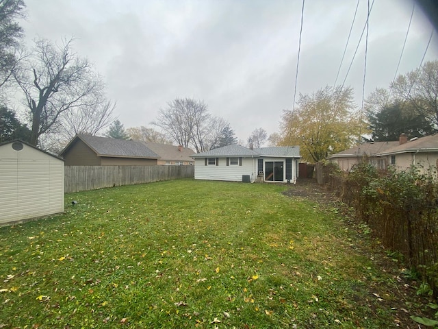 view of yard featuring an outbuilding, a fenced backyard, and a storage shed