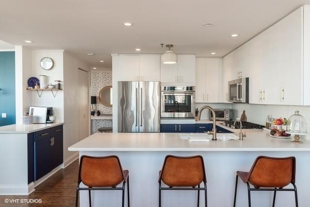 kitchen with appliances with stainless steel finishes, white cabinetry, and a kitchen breakfast bar