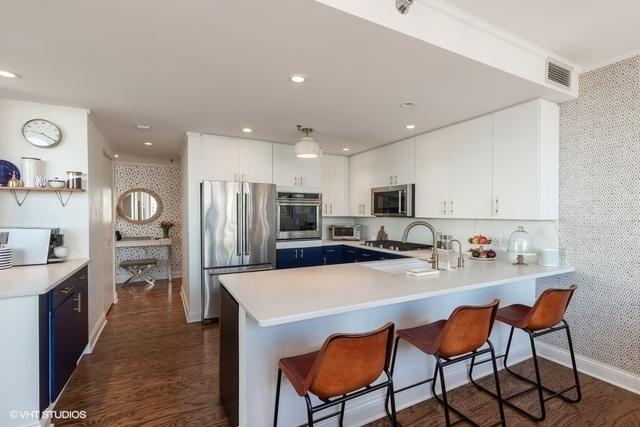 kitchen with kitchen peninsula, appliances with stainless steel finishes, white cabinets, and a breakfast bar