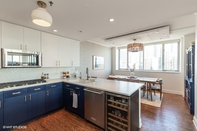 kitchen featuring appliances with stainless steel finishes, blue cabinetry, white cabinetry, kitchen peninsula, and hanging light fixtures