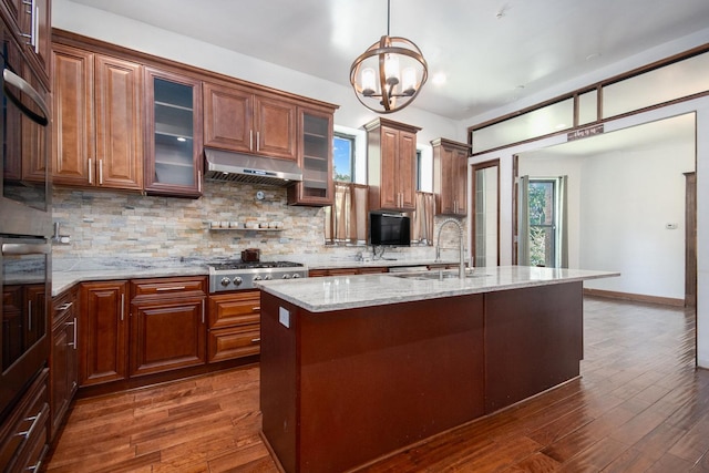 kitchen with a center island with sink, decorative backsplash, stainless steel gas cooktop, and an inviting chandelier