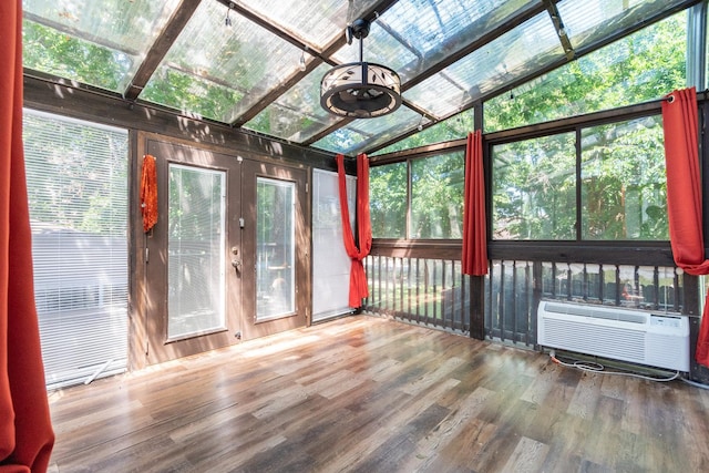 unfurnished sunroom featuring lofted ceiling and an AC wall unit