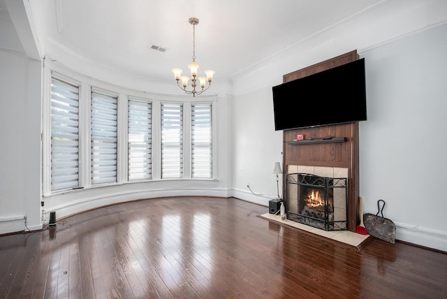 unfurnished living room with hardwood / wood-style flooring, a fireplace, and a notable chandelier