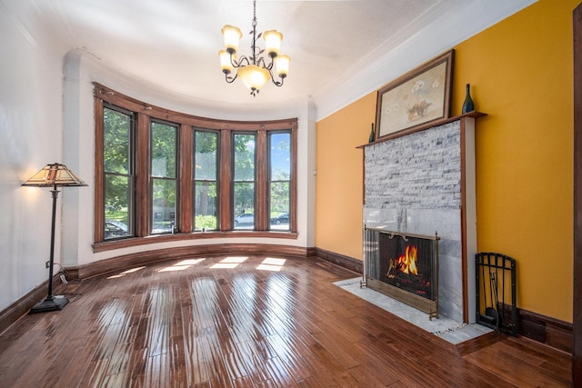 unfurnished living room featuring a fireplace, hardwood / wood-style floors, an inviting chandelier, and crown molding