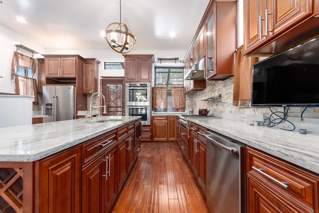 kitchen with appliances with stainless steel finishes, backsplash, sink, a chandelier, and hanging light fixtures