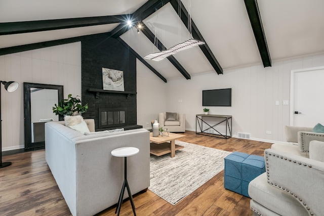 living room with vaulted ceiling with beams, wood walls, a fireplace, and hardwood / wood-style flooring