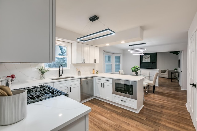 kitchen with built in microwave, dishwasher, white cabinets, and decorative light fixtures