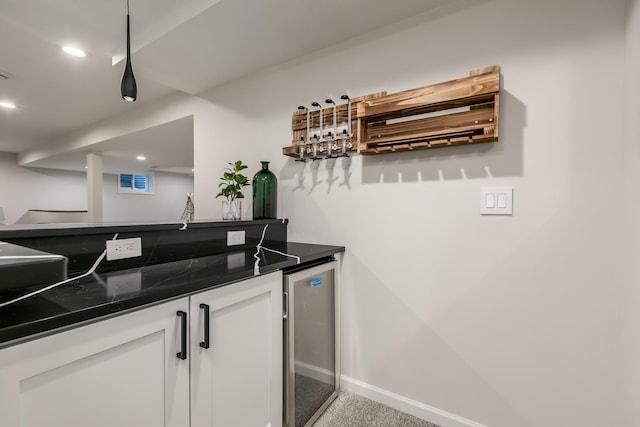 bar with dark stone countertops, white cabinetry, light colored carpet, and beverage cooler