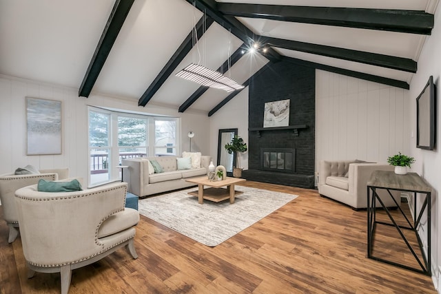 living room featuring wood-type flooring, vaulted ceiling with beams, a large fireplace, and wood walls