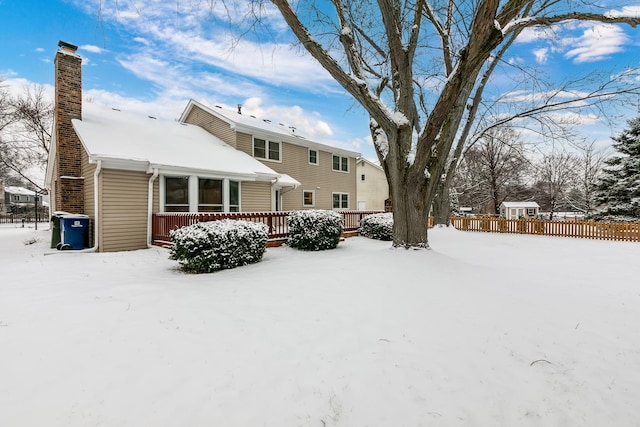 snow covered back of property with a deck