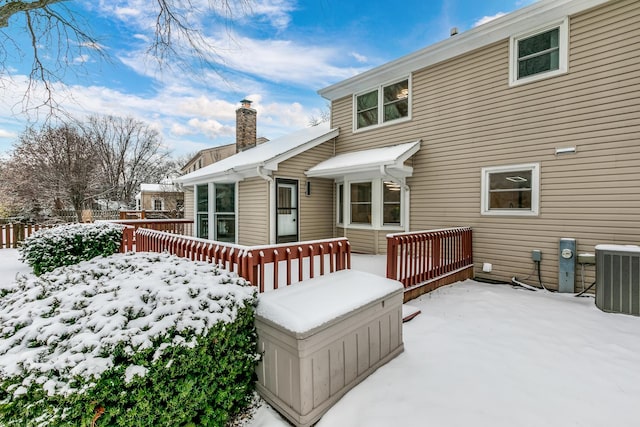 snow covered house with a wooden deck and central air condition unit