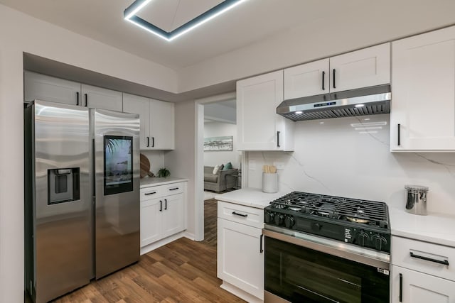 kitchen with white cabinets, appliances with stainless steel finishes, dark hardwood / wood-style floors, and tasteful backsplash