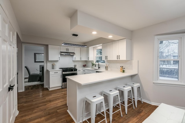 kitchen with decorative backsplash, sink, white cabinets, stainless steel gas stove, and dark hardwood / wood-style floors