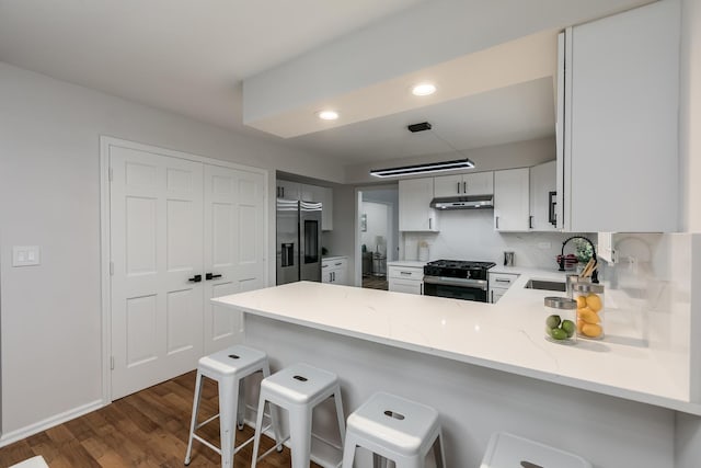 kitchen featuring sink, kitchen peninsula, a breakfast bar, white cabinets, and appliances with stainless steel finishes