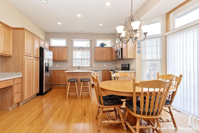 dining room featuring a healthy amount of sunlight, light hardwood / wood-style floors, and an inviting chandelier