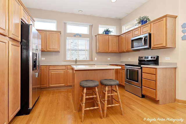 kitchen with a breakfast bar, light wood-type flooring, a center island, and stainless steel appliances