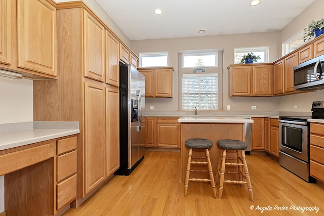 kitchen featuring a breakfast bar, a kitchen island, stainless steel appliances, and light hardwood / wood-style floors