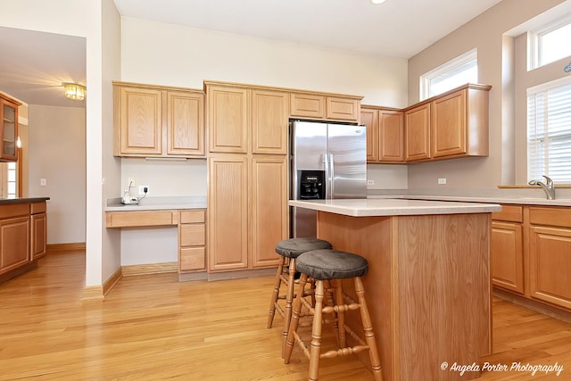 kitchen with a center island, a kitchen bar, light wood-type flooring, and stainless steel refrigerator with ice dispenser