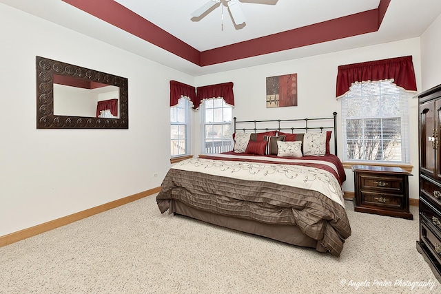 bedroom featuring carpet floors, a raised ceiling, and ceiling fan