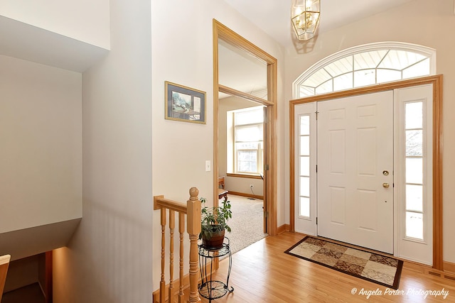 foyer entrance with light wood-type flooring and a notable chandelier