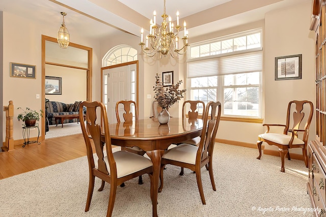 dining space with light hardwood / wood-style flooring and an inviting chandelier